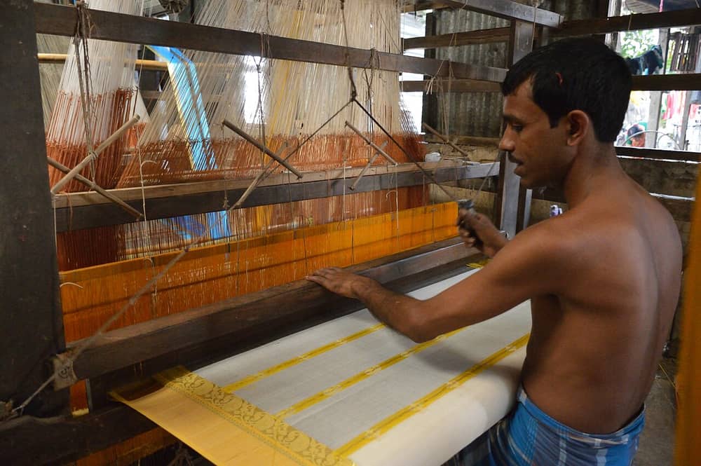 Hands guiding silk threads on a handloom